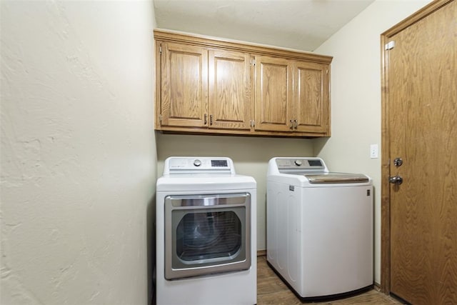 laundry area with washer and dryer, cabinet space, and wood finished floors