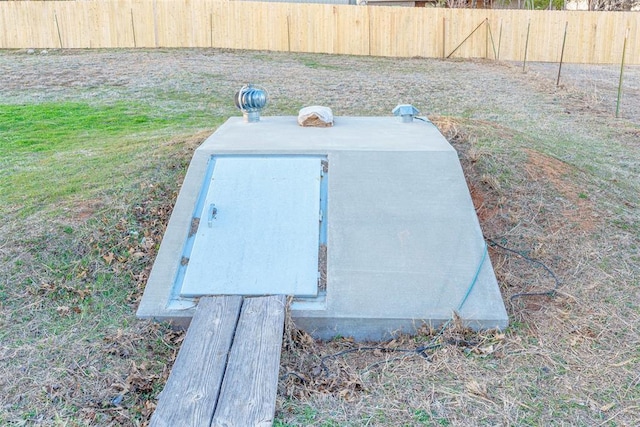 entry to storm shelter featuring fence and a lawn