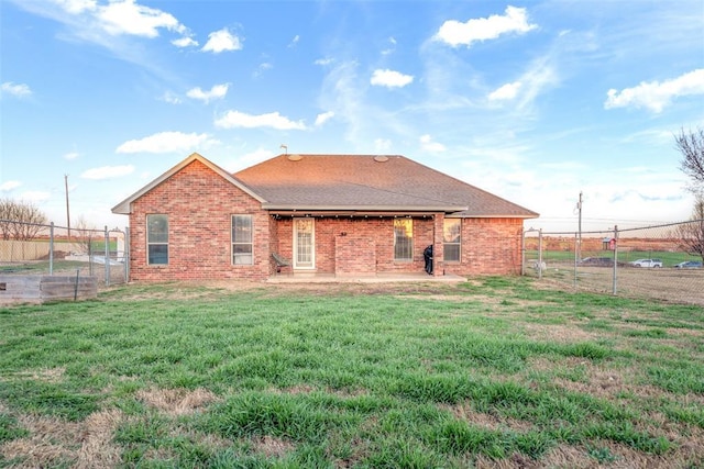 back of property with brick siding, fence, roof with shingles, a yard, and a patio