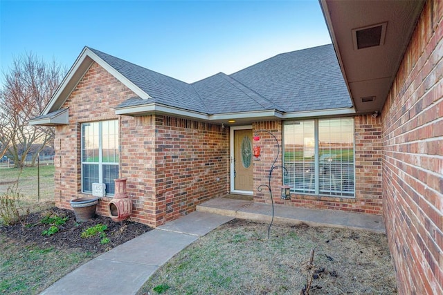 entrance to property with brick siding and roof with shingles