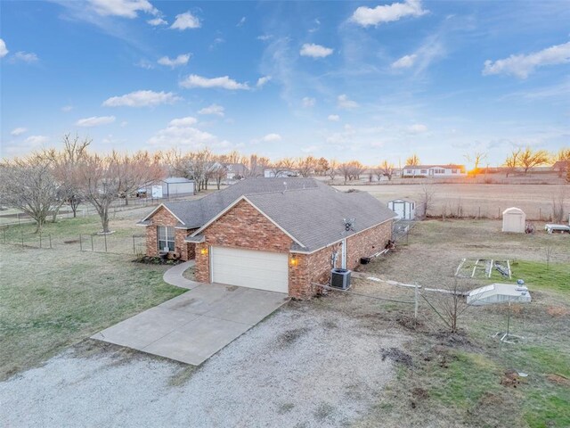 view of front facade featuring fence, central AC, concrete driveway, a garage, and brick siding