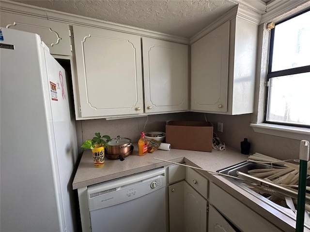 kitchen featuring a textured ceiling, light countertops, white appliances, and white cabinetry