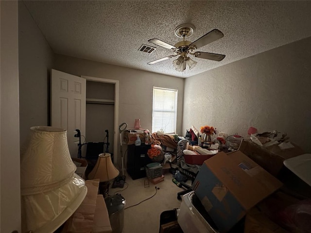 bedroom with visible vents, a textured wall, ceiling fan, carpet, and a textured ceiling