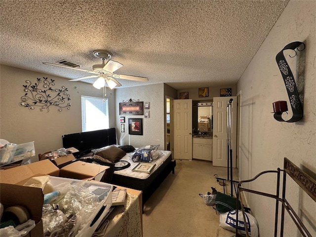 bedroom featuring visible vents, a textured wall, a ceiling fan, light carpet, and a textured ceiling