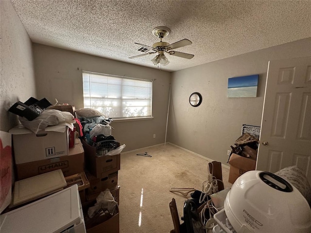 carpeted bedroom featuring a textured ceiling, a textured wall, a ceiling fan, and baseboards