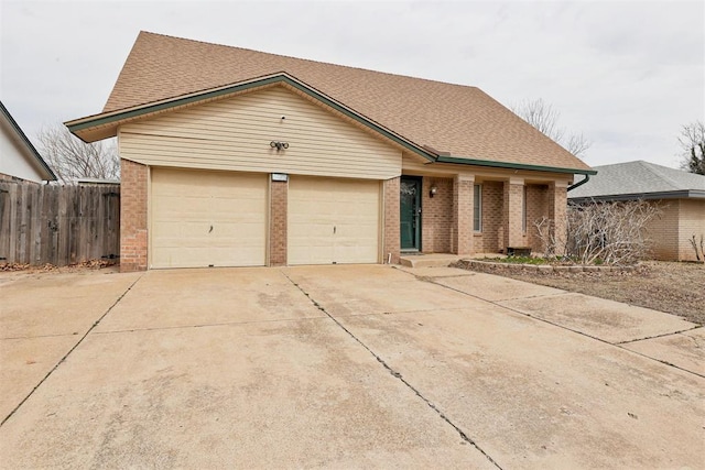 single story home featuring a garage, concrete driveway, brick siding, and fence