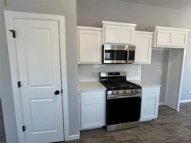 kitchen featuring tasteful backsplash, light countertops, appliances with stainless steel finishes, white cabinetry, and baseboards