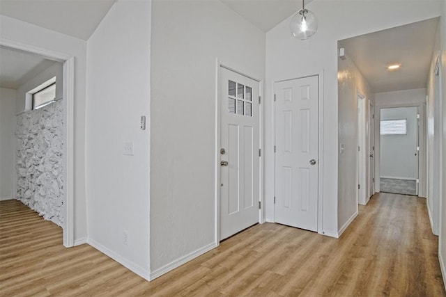 hall featuring light wood-style flooring and baseboards