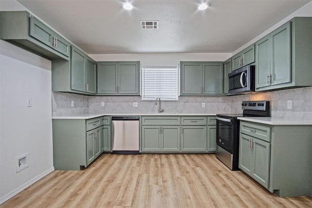 kitchen with stainless steel appliances, visible vents, a sink, and green cabinets