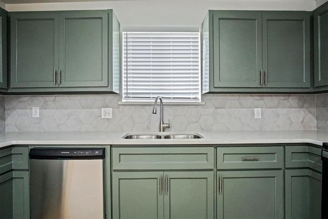 kitchen with light countertops, backsplash, green cabinets, stainless steel dishwasher, and a sink