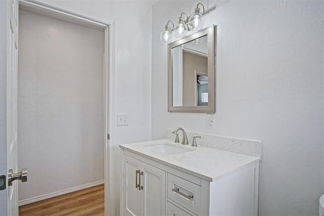 half bathroom featuring wood finished floors, vanity, and baseboards