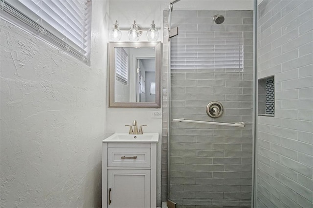 full bathroom featuring a textured wall, a stall shower, and vanity