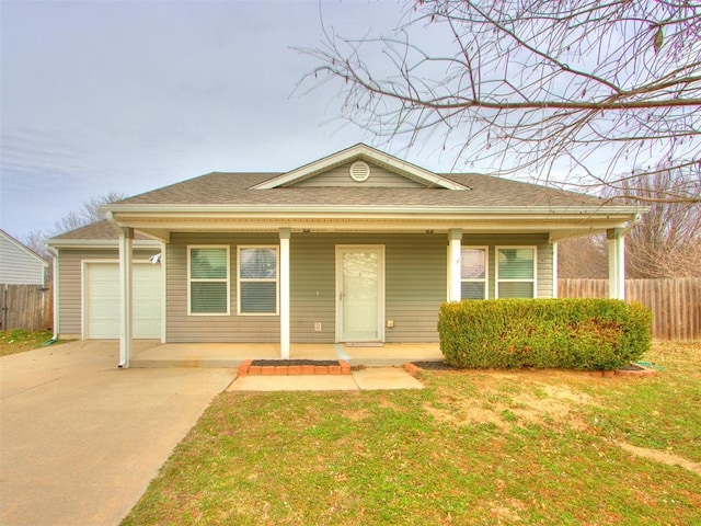 view of front of house with a shingled roof, concrete driveway, covered porch, fence, and a front yard