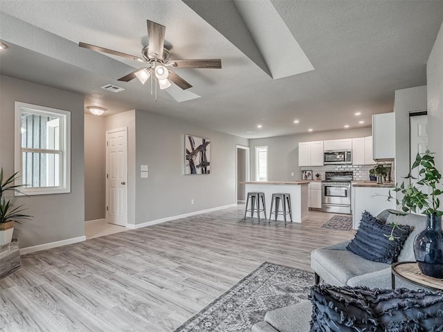 living area with light wood finished floors, plenty of natural light, visible vents, and baseboards