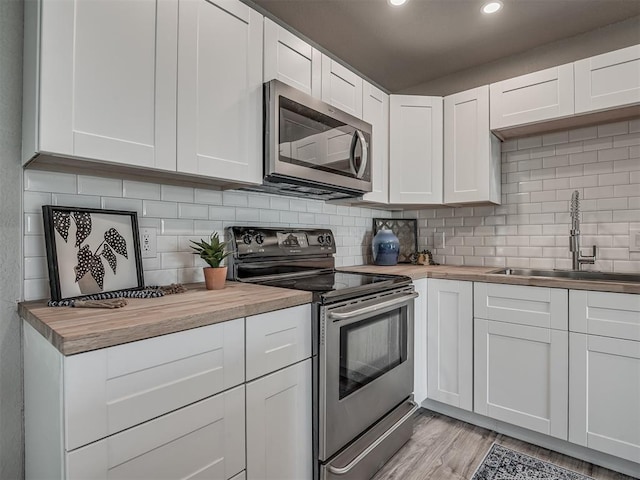 kitchen featuring stainless steel appliances, a sink, wood counters, and decorative backsplash