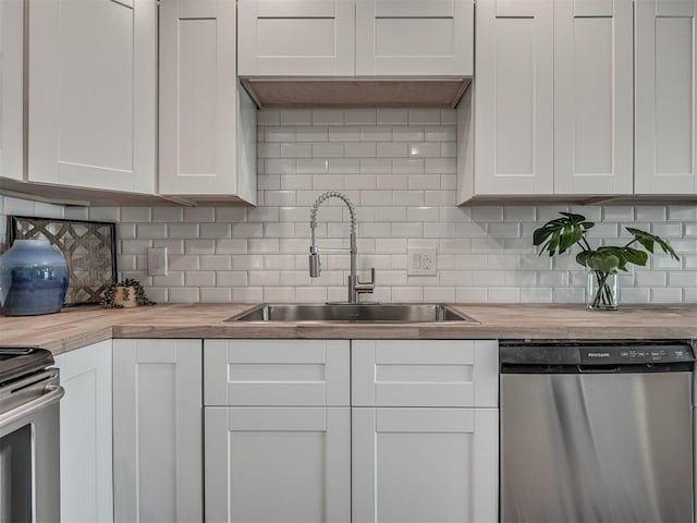 kitchen featuring appliances with stainless steel finishes, butcher block counters, a sink, and backsplash