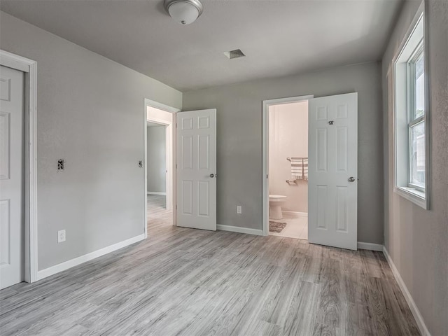 unfurnished bedroom featuring connected bathroom, baseboards, and wood finished floors