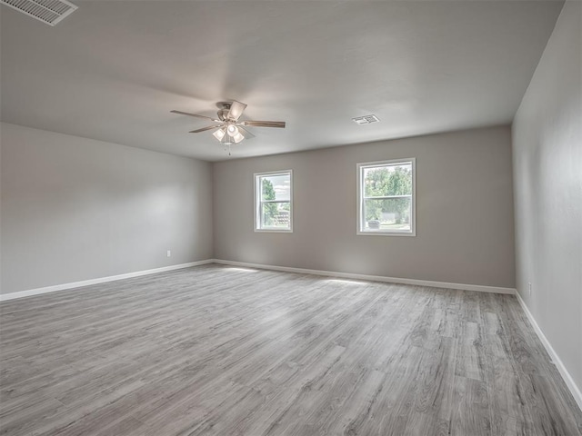 unfurnished room featuring visible vents, baseboards, and wood finished floors