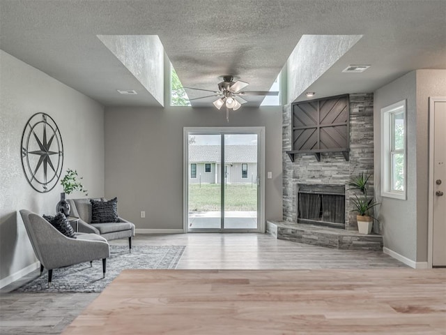 living room featuring a fireplace, wood finished floors, visible vents, and a healthy amount of sunlight