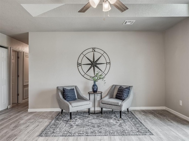 sitting room featuring ceiling fan, a textured ceiling, baseboards, and wood finished floors