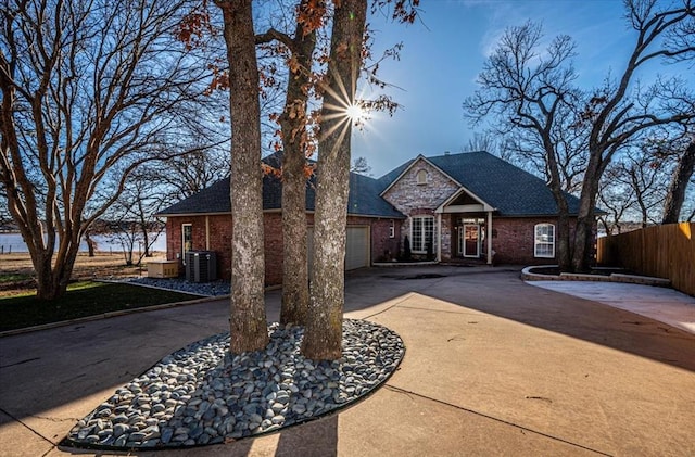 view of front of home featuring a garage, concrete driveway, brick siding, and fence