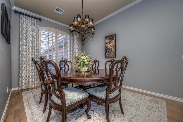 dining area featuring baseboards, visible vents, wood finished floors, and ornamental molding