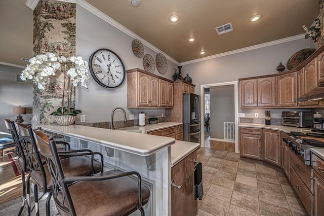 kitchen featuring stainless steel appliances, visible vents, a sink, a peninsula, and a kitchen bar