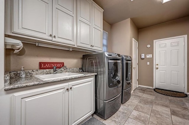 laundry area featuring a sink, cabinet space, baseboards, and washer and dryer