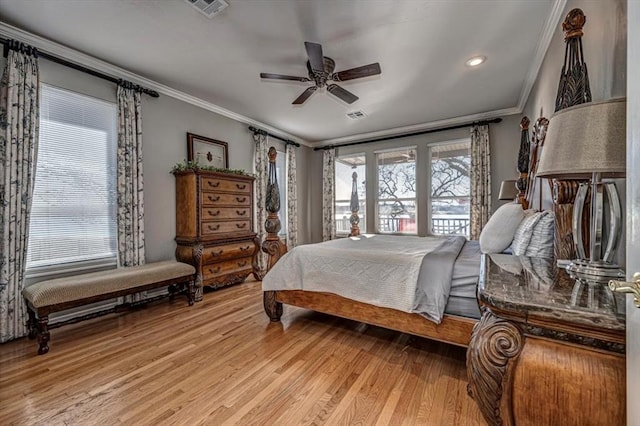 bedroom with ornamental molding, visible vents, light wood finished floors, and a ceiling fan