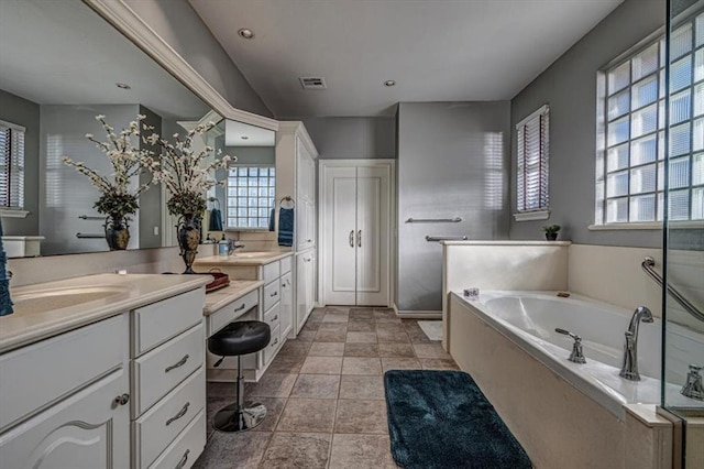 full bathroom featuring double vanity, a garden tub, visible vents, and a sink