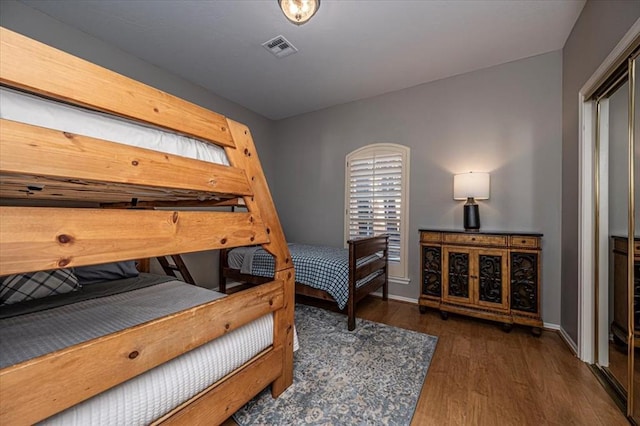 bedroom featuring baseboards, multiple windows, visible vents, and wood finished floors