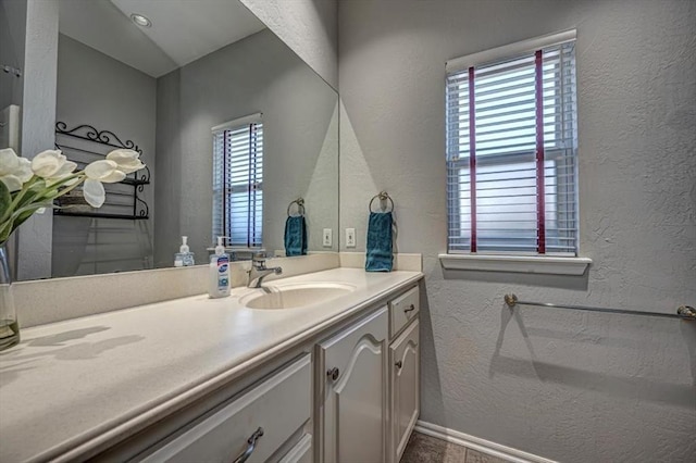 bathroom featuring a healthy amount of sunlight, a textured wall, and vanity