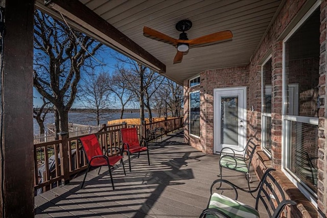 wooden terrace with a water view and ceiling fan