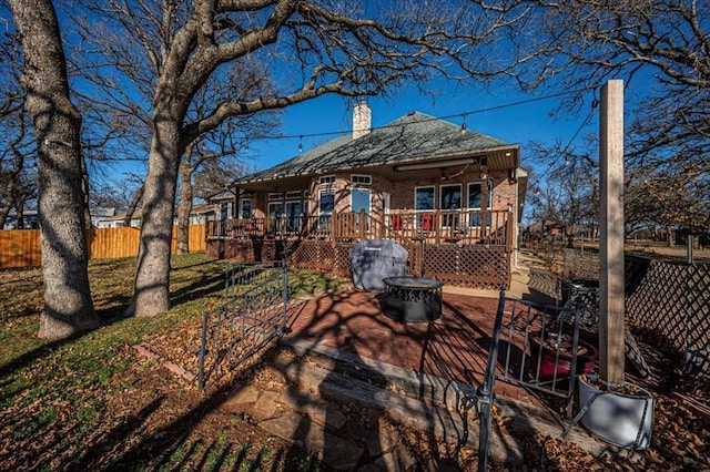 back of house with a fire pit, a chimney, fence, and a deck