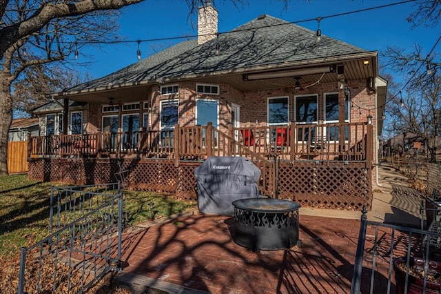 rear view of house with a shingled roof, a chimney, fence, and brick siding