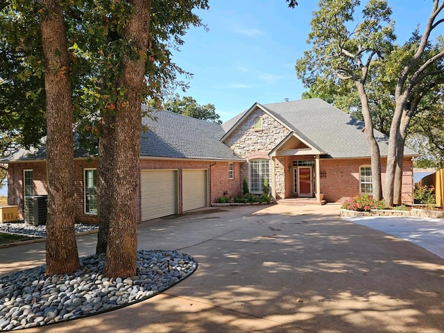 view of front facade with a garage, a shingled roof, brick siding, concrete driveway, and stone siding