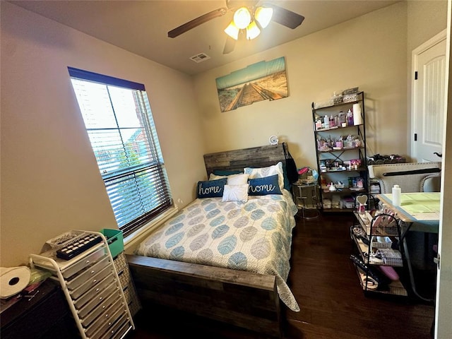 bedroom with a ceiling fan, visible vents, and wood finished floors