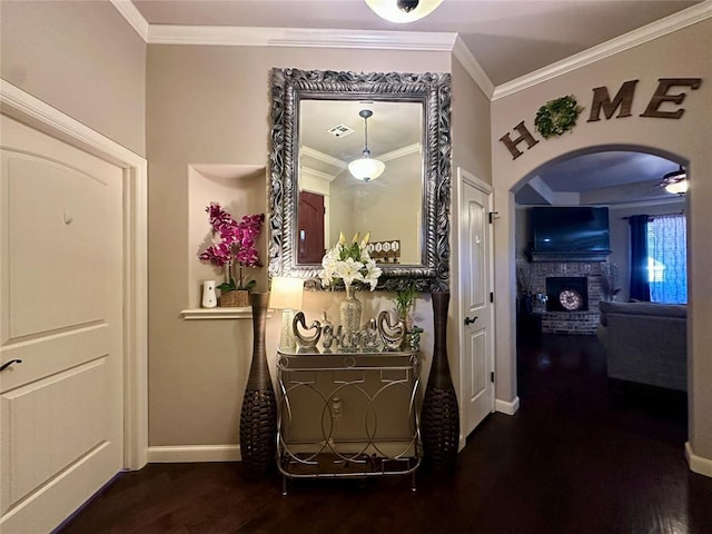 hallway with arched walkways, ornamental molding, wood finished floors, and baseboards