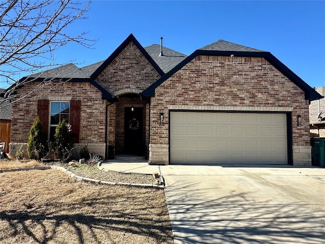 french provincial home featuring concrete driveway, brick siding, an attached garage, and roof with shingles