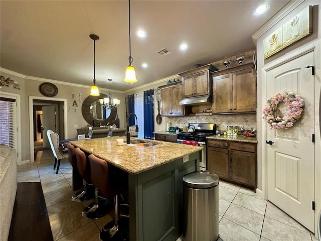 kitchen featuring visible vents, ornamental molding, gas stove, a sink, and under cabinet range hood