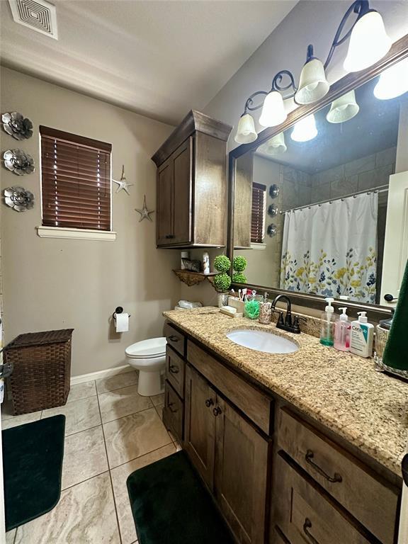 bathroom featuring curtained shower, toilet, vanity, visible vents, and baseboards