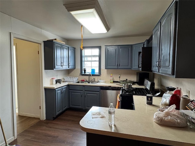 kitchen featuring stainless steel appliances, dark wood-style flooring, light countertops, and a sink