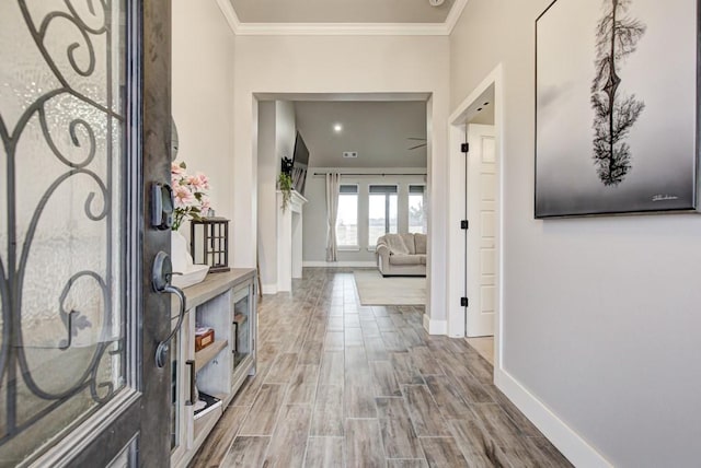 hallway featuring baseboards, crown molding, and wood finish floors