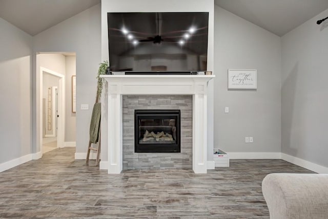 living area featuring a tile fireplace, vaulted ceiling, baseboards, and wood finished floors