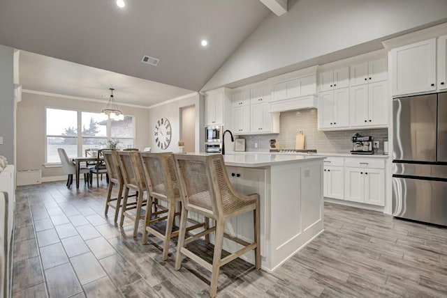 kitchen featuring tasteful backsplash, light countertops, visible vents, appliances with stainless steel finishes, and an island with sink