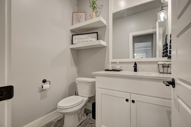 bathroom with toilet, baseboards, and vanity