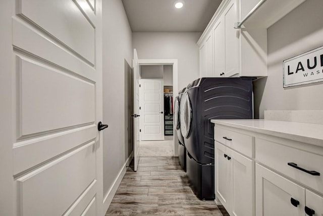 washroom with light wood finished floors, washing machine and clothes dryer, cabinet space, and recessed lighting