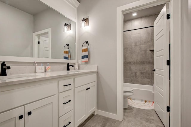 bathroom featuring double vanity, a sink, toilet, and baseboards