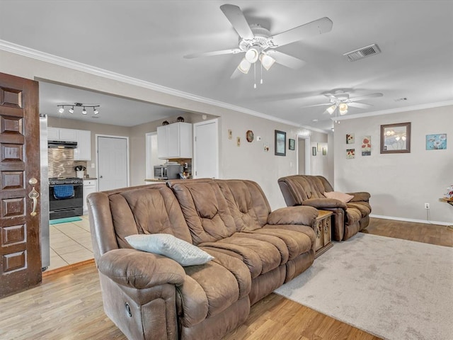 living room featuring crown molding, baseboards, visible vents, and light wood-style floors