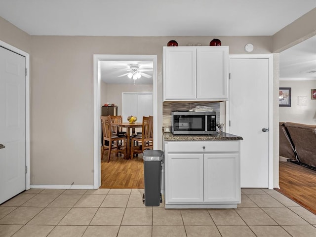 kitchen with light tile patterned floors, stainless steel microwave, a ceiling fan, and white cabinets